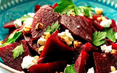 Ein köstlicher Rote Bete Feta Salat mit Nüssen und frischer Petersilie, serviert in einer blauen Schüssel.