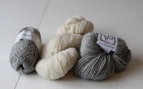 Mjuka garnnystan i grått och naturvitt. Perfekt ullgarn som inte kliar, redo att bli ditt nästa stickprojekt.