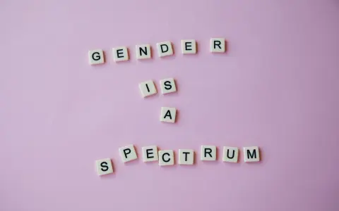 Litery układają napis "GENDER IS A SPECTRUM", podkreślając, że dysforia i niezgodność płciowa są częścią szerokiego spektrum tożsamości.