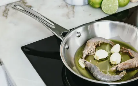 Camarones y ajo en sartén de acero inoxidable, un paso para como curar una sartén de acero inoxidable.