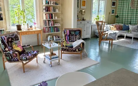 Ljust och luftigt vardagsrum med två färgstarka fåtöljer, bokhyllor och en soffgrupp. En harmonisk känsla som påminner om feng shui vardagsrum.