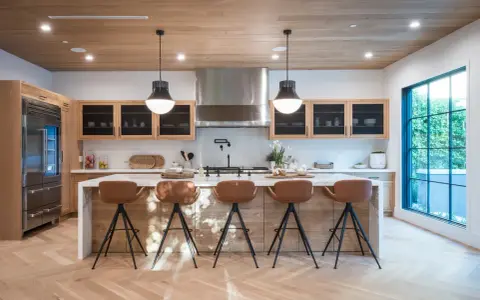 Cocina moderna con isla central y taburetes de cuero marrón. Las medidas del taburete son ideales para la altura de la isla.