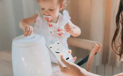 Niña interactúa con humidificador mientras una mano controla la app para humidificar el ambiente.