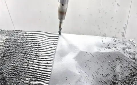CNC-Fräser bearbeitet eine **Aluminiumstange**, die in Wellen und Rillen geformt wird. Späne bedecken die Oberfläche.