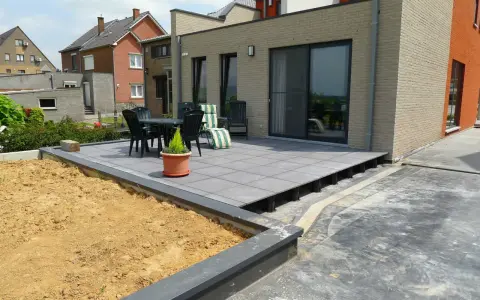 Terrasse avec dalles grises sur plots, prête à accueillir une dalle béton. Table et chaises sur le côté.