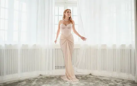 Molly Sandén i en ljusrosa klänning vid ett fönster, redo för Elle-galan.