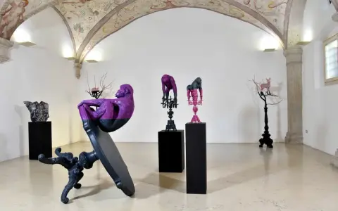 Sculture di scimmie e cervi colorati, opere di **artisti contemporanei famosi**, in una galleria con affreschi sul soffitto.