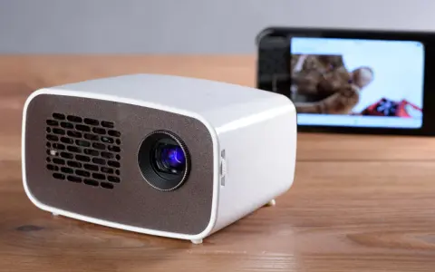 Kleiner Beamer mit Handy verbinden für Heimkino. Ein Smartphone zeigt ein Bild, während der Beamer bereit ist.