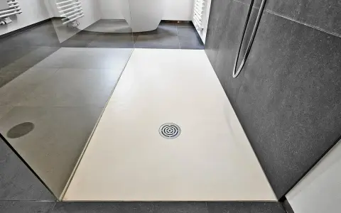Receveur de douche blanc, quelle matière choisir pour un style moderne ? Sol gris, paroi sombre.