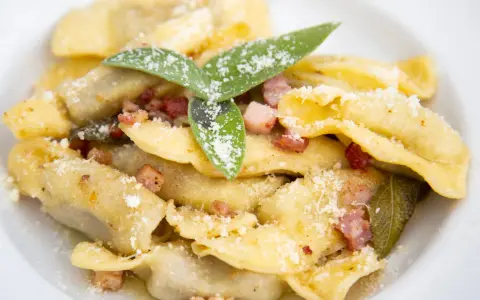 Ravioli fatti in casa con pancetta croccante, salvia e parmigiano, un assaggio dei piatti tipici bergamaschi.