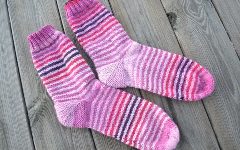 Två par randiga sockor i rosa och lila toner ligger på en träyta.