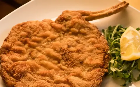 Cotolette al forno dorate e croccanti, servite con rucola fresca e una fetta di limone.