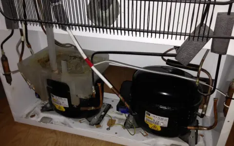 Kylskåpets kompressorer och kondensor. Det låter som en borr när kylskåpet går.