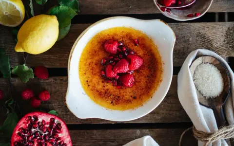 Creme Brulee mit Himbeeren und Granatapfelkernen. Dazu passen Zitronen und Zucker.