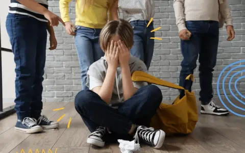 Dziecko zakrywa twarz, otoczone przez inne dzieci, które wskazują palcami. To obraz tego, czym jest bullying.