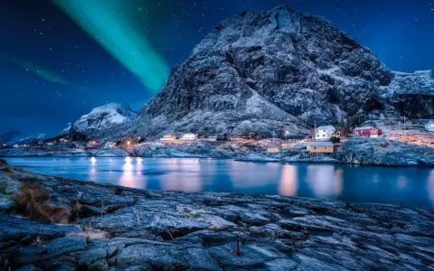 Ein malerisches Dorf in Norwegen im Winter, beleuchtet von den Nordlichtern und dem Sternenhimmel.