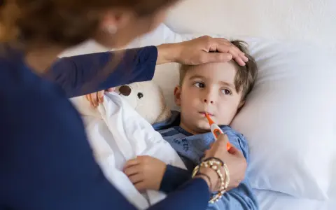 Chłopiec leży w łóżku, mama mierzy mu temperaturę. Znowu choruje, to już drugi raz w tym miesiącu.