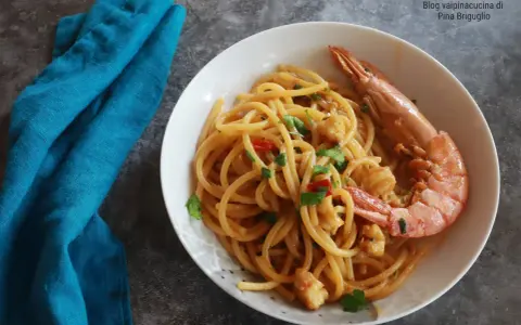 Spaghetti con gamberoni surgelati, un piatto gustoso e veloce. Un gamberone intero adorna la pasta condita con pomodorini e prezzemolo.