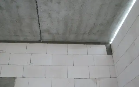 Betonowy strop z widocznym pęknięciem nad ścianą z białych pustaków.