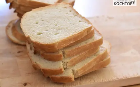 Gestapelte Scheiben eines hellen Sandwichbrots auf einem Holzbrett. Perfekt für ein einfaches Sandwich brot rezept.