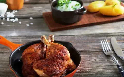 Złociste udka z airfryer w pomarańczowej patelni, obok ziemniaczki i surówka z ogórka. Pyszny obiad gotowy!