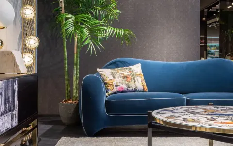 Divano blu petrolio con cuscino decorato. Abbinamenti eleganti con tavolino e arredi moderni.