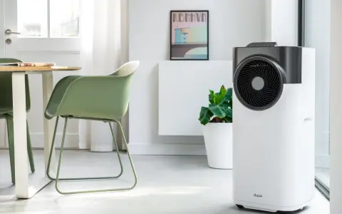 Le climatiseur pure blizzard, blanc et gris, trône dans un salon moderne aux côtés d'une plante verte et d'un tableau.