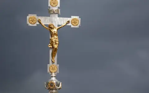 Ein goldenes Kruzifix mit Jesus vor dramatischem Himmel. Die Frage, wie lange dauert die Osterzeit, hallt nach.