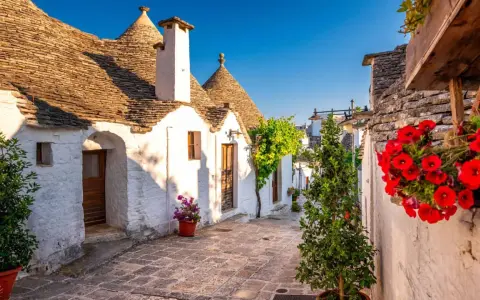 Un vicolo fiorito tra i trulli di Alberobello, un'idea perfetta per sapere dove andare in primavera.