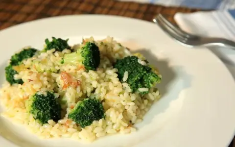 Delicioso arroz con brócoli cremoso, servido en un plato blanco con un tenedor al lado.