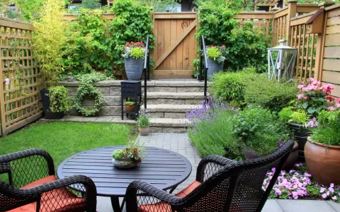 Un petit jardin aménagé avec une table, des chaises, des plantes et une porte en bois.