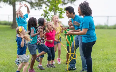 Des enfants et des animateurs jouent à la corde à sauter dans un parc.