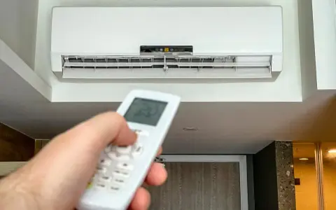 Mano ajustando el control remoto del aire acondicionado a 20 grados, ideal para saber a cuanto poner el aire acondicionado en verano y refrescar el hogar.