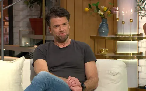 Peter Magnusson sitter i en soffa, kanske redo att prata om sina filmer och tv-program.