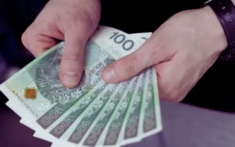 Dłonie trzymają stos banknotów 100 zł. Czy to wypłata z UoP?