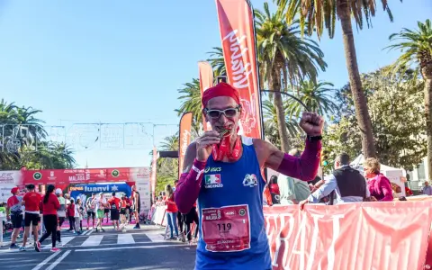 Lächelnder Läufer mit Medaille und rotem Kopftuch feiert seinen Erfolg beim Malaga Marathon.