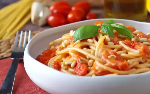 Spaghetti con pomodorini, pinoli e basilico, un'idea per sughi estivi per pasta freschi e veloci.