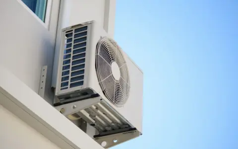 Unidad exterior de aire acondicionado montada en la pared de una terraza cerrada, lista para refrescar el ambiente.
