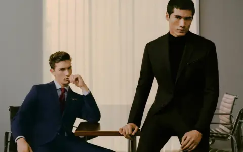 Dos hombres con trajes elegantes, uno azul y otro negro, demuestran el estilo business casual en una oficina moderna.