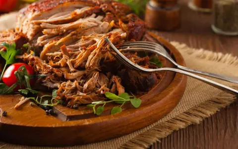 Saftiges Pulled Pork, perfekt zubereitet mit einem aromatischen pulled pork rub, liegt auf einem Holzbrett. Gabeln deuten auf den Genuss hin.