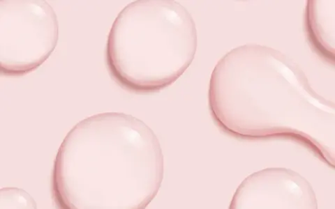 Gocce rosa su sfondo rosa, simili a quelle che si trovano in prodotti con cetearyl alcohol cos'è, un ingrediente emolliente.