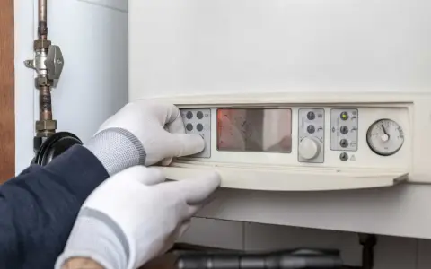 Mani guantate impostano un pannello di controllo, forse per capire la differenza tra caldaia e scaldabagno.
