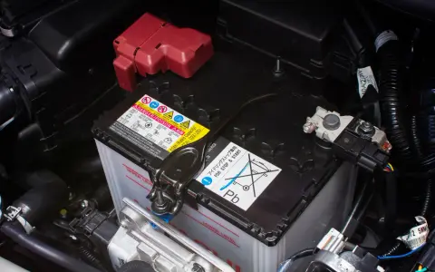 Autobatterie im Motorraum, mit Warnhinweisen. Die Batterie ist tiefentladen und muss ersetzt werden.