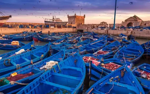 Port w Maroku, pełen błękitnych łodzi rybackich, z twierdzą w tle. Idealna pogoda na wrzesień, by podziwiać zachód słońca nad Atlantykiem.