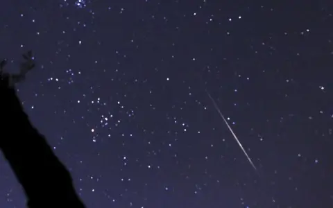 En stjärnklar natt med en meteor som drar en ljusstrimma över himlen, ett av många olika ljusfenomen på himlen.