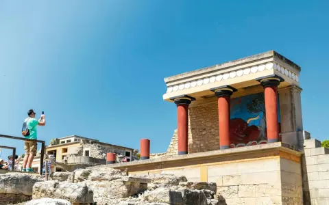 Zwiedzający robi zdjęcie fresku z bykiem w starożytnym pałacu w Knossos.