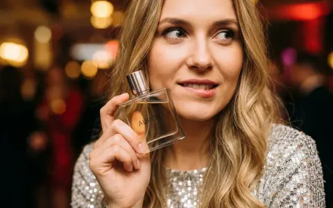 Kobieta z flakonem perfum "Aurora" zastanawia się, czy ma w sobie to coś, co przyciąga mężczyzn.