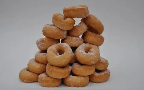 Pile de donuts dorés saupoudrés de sucre, parfaits pour une recette facile de donuts maison.