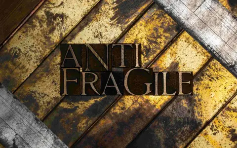 Lettere di metallo con la scritta "ANTI FRAGILE" su uno sfondo ruvido e dorato, simbolo di antifragilità e resilienza.