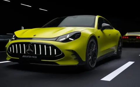 Jaskrawożółty Mercedes-AMG GT 63 z czarnym dachem i felgami, na ciemnym tle z białymi pasami drogowymi.